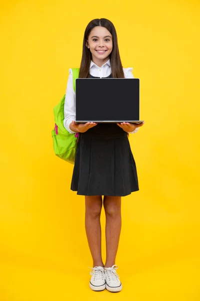 Teen schoolgirl hold laptop on isolated studio background. Cchool student learning online, webinar, video lesson, distance education. Screen of laptop computer with copy space mockup