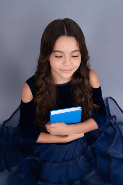 Dreaming schoolgirl in dress hold book and copybook ready to learn. School children dream on isolated grey background