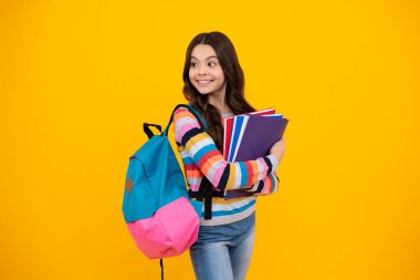 School girl hold copybook and book on yellow isolated studio background. School and education concept. Teenager girl in school uniform. Happy teenager, positive and smiling emotions of teen girl