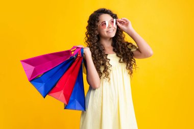 Happy teenager portrait. Funny teen girl hold shopping bag enjoying sale isolated on yellow. Portrait of teenager schoolgirl is ready to go shopping. Smiling girl