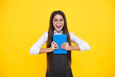 Back to school. Teenager schoolgirl with book ready to learn. School girl children on isolated yellow studio background. Excited face, cheerful emotions of teenager girl