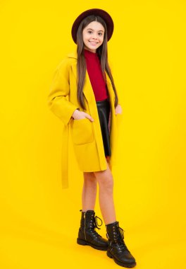 Elegant fashion teenager child girl in autumn coat posing in studio. Trends kids clothes. Happy teenager portrait. Smiling girl