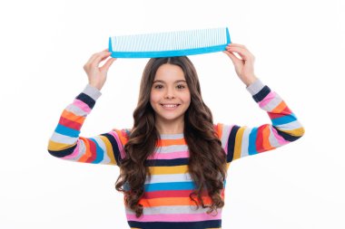 Child with long hair holding comb hairbrush for combing, beauty. Conditioner shampoo hair. Beauty kids salon. Child hairstyle. Happy girl face, positive and smiling emotions