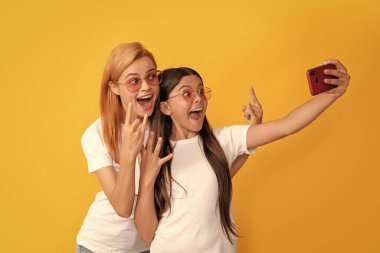 Anne-kız vloglama. Online iletişim. Anne ve çocuk blogcuları. Mutlu kadın ve kız akıllı telefonla selfie çekiyorlar. Selfie ailesi. Modern hayat. mobil teknoloji. Video çağrısı alınıyor.