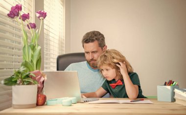 back to school. comcentrated father and son use computer at home. family blog. boy do homework with private teacher. webinar video lesson. online education on laptop. homeschooling and elearning.