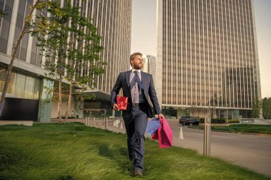 Hediyeli kutusu olan yakışıklı bir adam. Girişimci doğum günü hediyesi taşır. Adam alışveriş torbalarını tutuyor. Erkekler günü. Paketleri olan mutlu bir iş adamı. Satış ve indirim. Ona sürpriz yapacağım. Sevgilim olur musun? Boks günü.