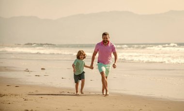 Mutlu baba ve oğul yaz plajında koşuyor..