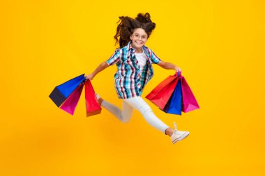 Amazed teen girl. Girl teenager with shopping bags isolated on yellow backgound. Shopping and sale concept. Excited expression, cheerful and glad