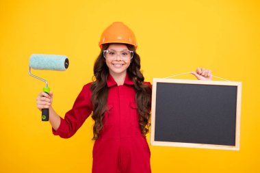 Atölyedeki ressam. Yenileme ve onarım. Kasklı, fırçalı genç bir kız. Kasklı çocuk. İnşaat alanında boyacı çocuk. Genç kızın mutlu ve gülümseyen duyguları