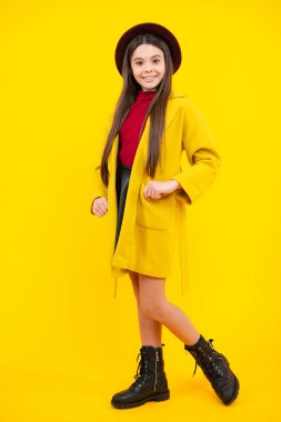 Teenager child girl casual autumn coat posing isolated on yellow background in studio. Kids lifestyle concept. Autumn clothes