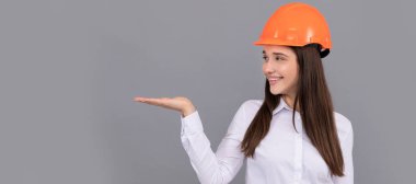 Woman isolated face portrait, banner with mock up copy space. entrepreneur in helmet. safety business. labor day. happy woman worker presenting product