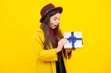 Child with gift present box on isolated studio background. Gifting for kids birthday. Excited teenager, glad amazed and overjoyed emotions