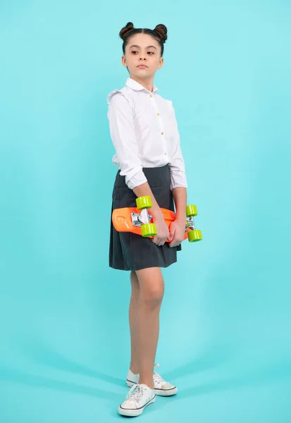 Teen school girl with skateboard on studio isolated background. Spring schoolgirl trend, urban teenager style