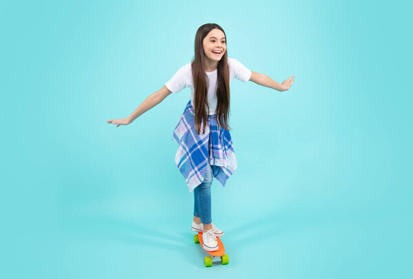 Teenagers lifestyle, casual youth culture. Teen girl with skateboard over isolated studio background. Cool modern teenager in stylish clothes. Happy teenager, positive and smiling emotions.