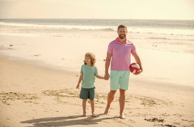 kid and dad walking on beach in summer vacation holding ball, summer.
