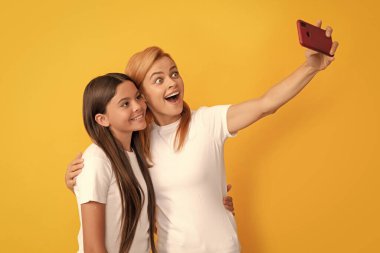 mom and kid blogging. happy woman and girl take selfie with mobile phone. selfie family. modern life. mobile technology. having video call. mother and daughter vlogging. online communication.