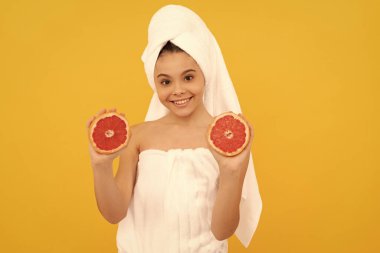 Sarı arka planda greyfurtlu havluyla mutlu bir kız..