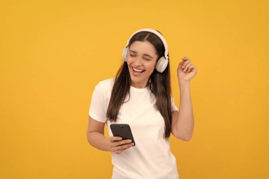 Kulaklıklı mutlu kız. Kablosuz kulaklıkla giyin. Modern eğitim çevrimiçi. İletişim teknolojisi. Akıllı telefondan kadın sohbeti. Müzik dinliyordum. Etkilendirici günlüğü.