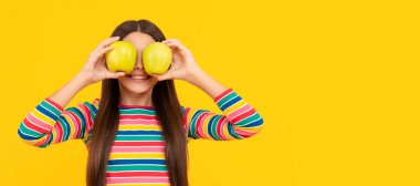 Apples improve your eyesight. Happy child hold apples at eyes. Fruit for good eye health. Child girl portrait with apple, horizontal poster. Banner header with copy space