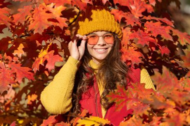 happy teen kid in sunglasses at autumn leaves on natural background.