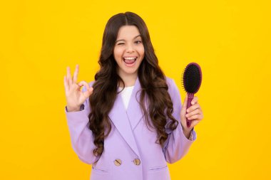 Child with long hair holding comb hairbrush for combing, beauty. Conditioner shampoo hair. Beauty kids salon. Child hairstyle. Excited teenager girl