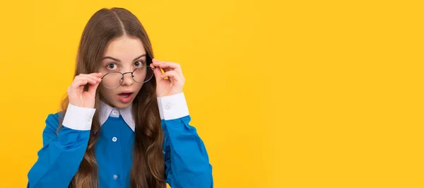 Just curious. Curious girl in eyeglasses. Nerdy-looking kid yellow background. Back to school. Child face, horizontal poster, teenager girl isolated portrait, banner with copy space