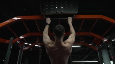 back view of muscular athlete pullup in sport gym. sport athlete with pullup in gym. athlete pullup with sport pullup equipment in gym.