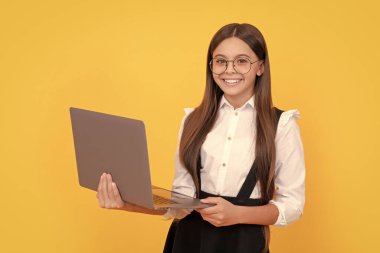 Okul üniformalı ve gözlüklü mutlu çocuk laptopta ders çalışıyor, okula dönüyor..
