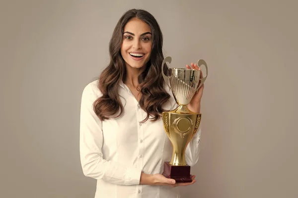 Business woman holding a trophy. Businesswoman concept winner success. Smiling female with trophy isolated on gray background