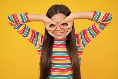 Güzel genç kız parmak izlerine bak. Sarı arka planda izole edilmiş aptal şekiller. Komik çocuk suratı