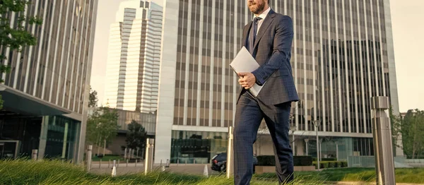 cropped businessman in suit walking with laptop outside the office, agile business.