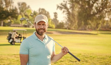 İnsanların yaşam tarzı. Yeşil çimlerin üzerinde adam üstüne adam gülüşü. Yaz etkinliği. Profesyonel açık hava sporu. Profesyonel golf sahasında erkek golfçü. Golf sopasıyla şapkalı golfçünün portresi..