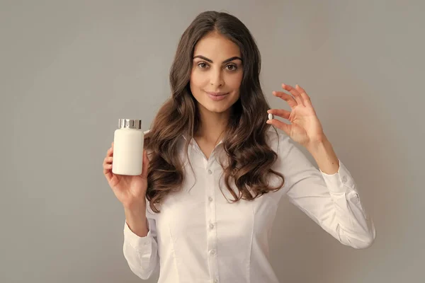 Woman with bottle pills. Woman holding white unlabeled medicine pills bottle. Vitamins, capsules or pills. Pharmacy, medicine and health care concept