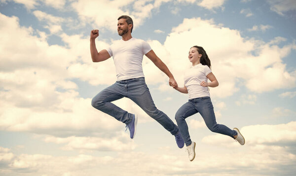 energetic father and daughter jump in sky.