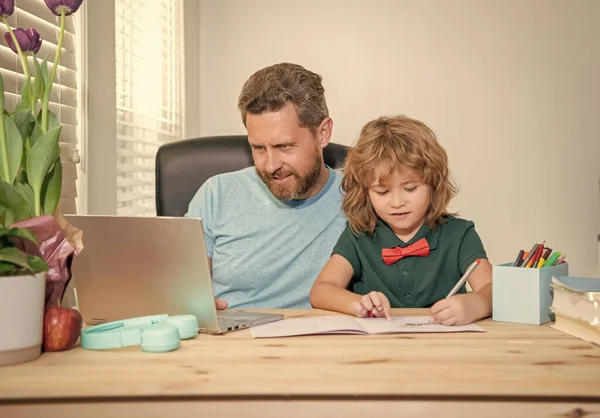 bearded dad or school private tutor teaching boy son with modern laptop, lesson online.