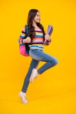 School girl hold copybook and book on yellow isolated studio background. School and education concept. Teenager girl in school uniform. Happy teenager, positive and smiling emotions of teen girl
