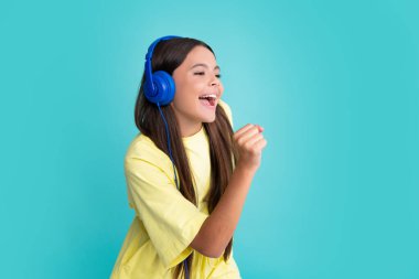 Child music concept. Teenager child girl dances in rhythm of melody, listens song in headphones. Child listening to music through earphones. Excited face, cheerful emotions of teenager girl