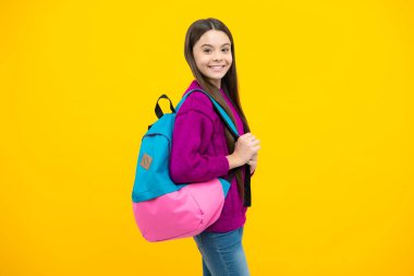 School girl in school uniform with school bag. Schoolchild teenager hold backpack on yellow isolated background