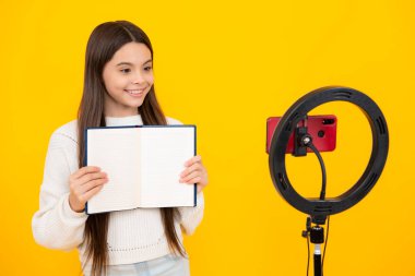 Young blogger school girl recording video for blog. Teen girl speaking in front of camera for vlog. Teenager working as blogger, recording video tutorial for blog