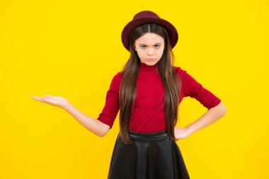 Close-up portrait of her she nice cute attractive cheerful amazed girl pointing aside on copy space isolated on yellow background. Angry face, upset emotions of teenager girl
