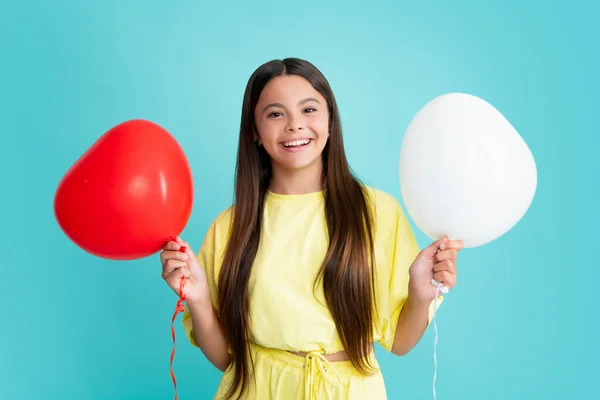 Happy girl face, positive and smiling emotions. Portrait of child teenage girl with heart balloon. Valentines day concept. Excited face, cheerful emotions of teenager girl