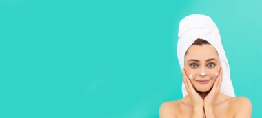 young lady apply face cream on blue background with copy space.