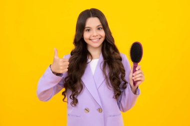 Teenager girl with long hair holding comb hairbrush for combing, beauty. Conditioner shampoo hair. Beauty kids salon. Child hairstyle. Happy face, positive and smiling emotions.