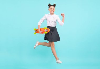 Teenagers youth casual culture. Jump and run. Teen girl with skateboard over isolated studio background. Teenager in fashion stylish clothes