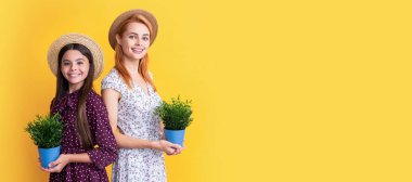 Mother and daughter kid banner, copy space, isolated background. smiling mother and daughter with potted plant on yellow background