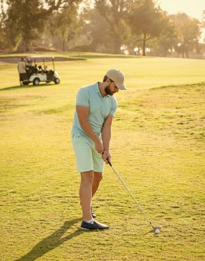 Profesyonel golf sahasında erkek golfçü. Golf sopasıyla şapkalı bir golfçü. İnsanların yaşam tarzı. Adam yeşil çimlerde oyun oynuyor. Yaz etkinliği. Profesyonel spor..