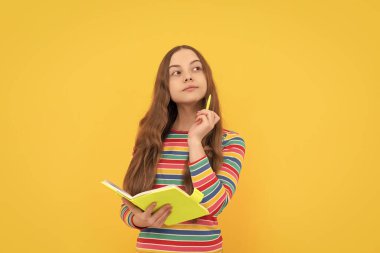 Düşünceli bir çocuk, elinde kalem ve defter tutarak okul kompozisyonunu düşünür. Sarı arka plan, hikaye..