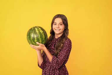 Sarı arka planda taze olgun karpuz meyvesi tutan mutlu çocuk, yaz mevsimi..