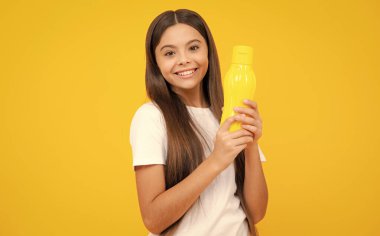 Gençler su şişesini sarıda tutuyor. Çocuk bakımı vücut sıvısı. Aktif eğlence ve su dengesi. Aktif ve sağlıklı çocuk su içer. Mutlu ergen portresi. Gülümseyen kız