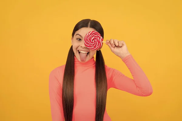 having fun. caramel candy shop. sweet childhood life. teen dental care. sweet tooth. yummy. amazed girl hold lollipop. lollipop child. kid with long hair hold lollypop. sugar candy on stick.